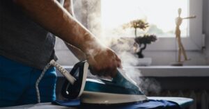 Steam ironing clothes on an ironing board near a bright window.