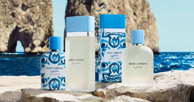 Dolce & Gabbana Light Blue perfume bottles displayed by the sea with rocky cliffs in the background
