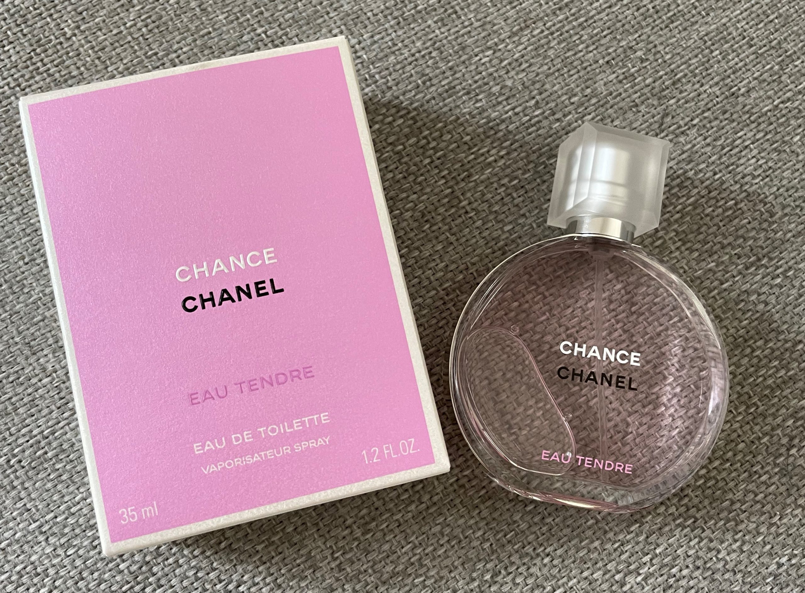 Chanel Chance Eau Tendre perfume bottle with pink box on textured fabric
