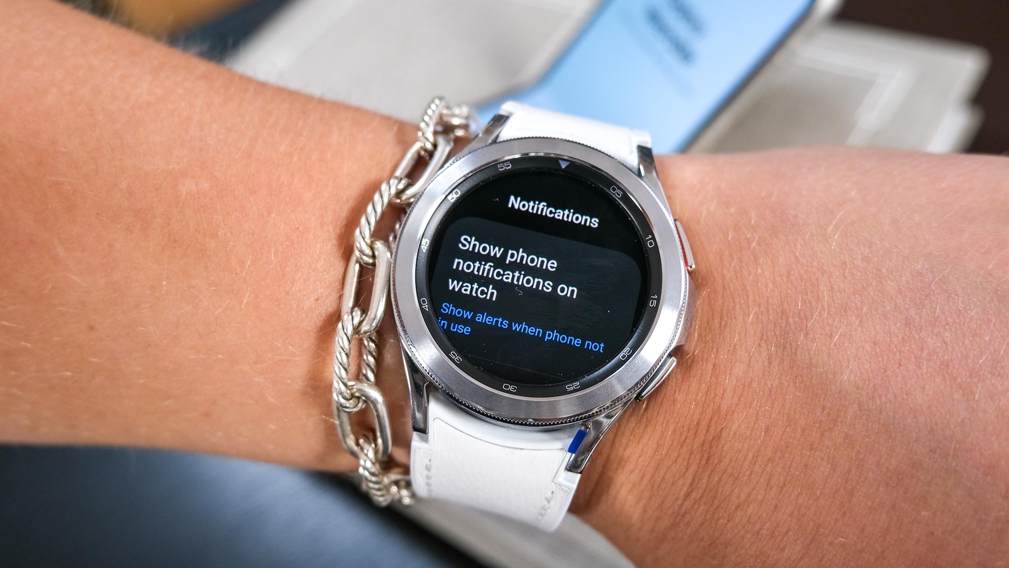 Round smartwatch with white strap showing notification settings on a wrist
