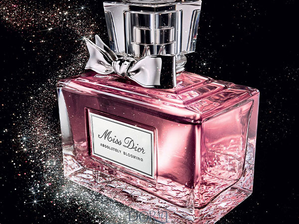 Miss Dior Absolutely Blooming pink perfume bottle with silver bow on a sparkling black background
