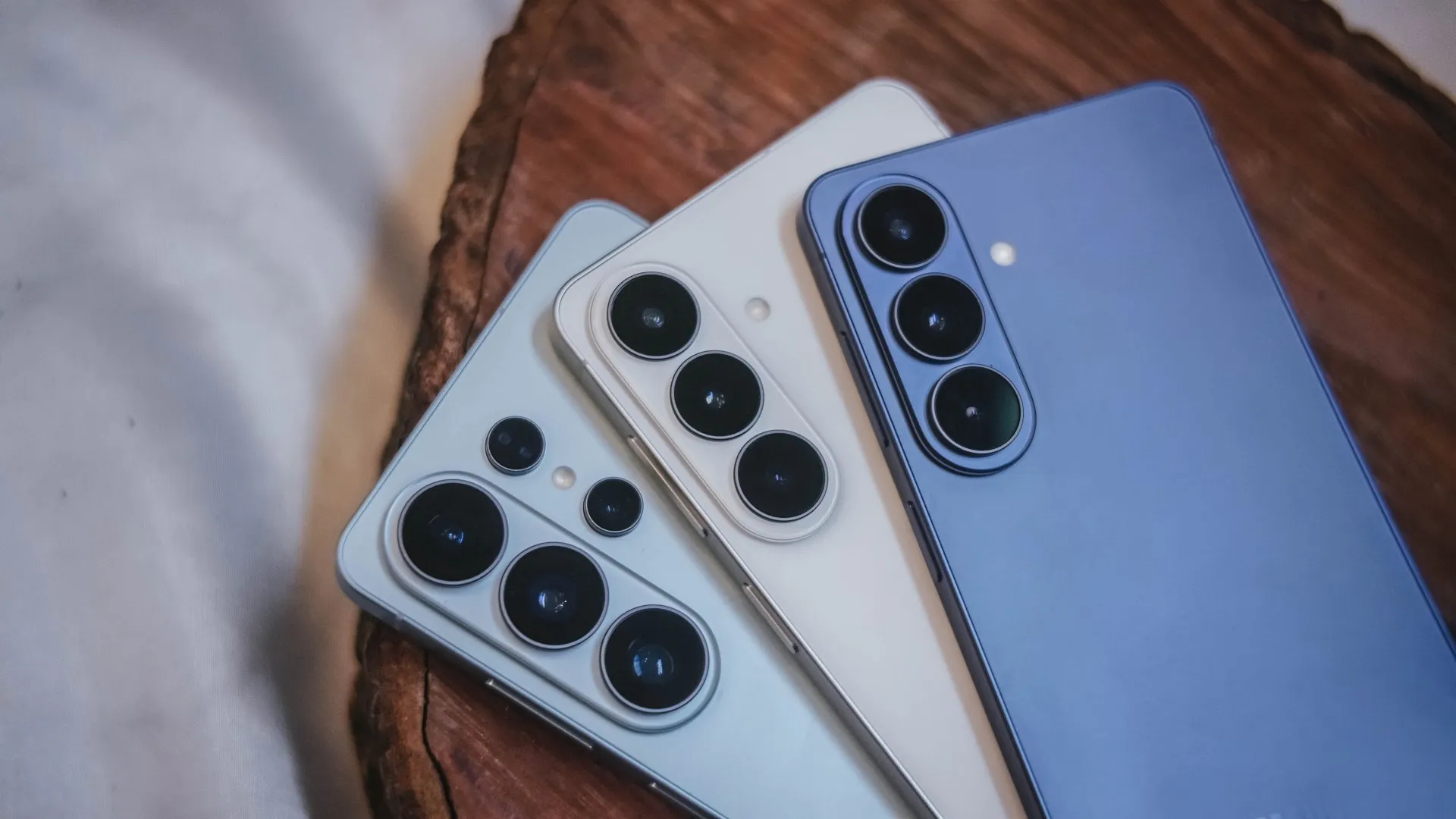 Samsung Galaxy S26, Galaxy S26 Plus and Galaxy S26 Ultra smartphones in multiple colors displayed together on a wooden surface. 