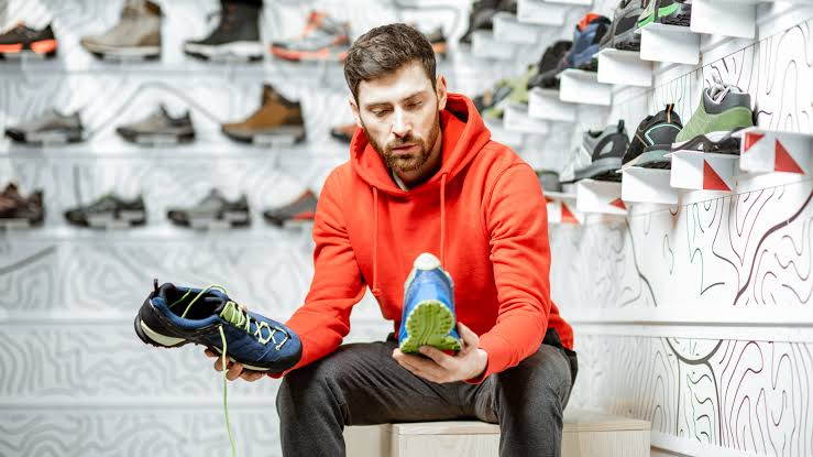 Person comparing running shoes in a footwear store.