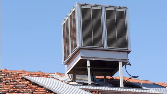 Rooftop evaporative cooler installed on a metal support frame under a clear sky