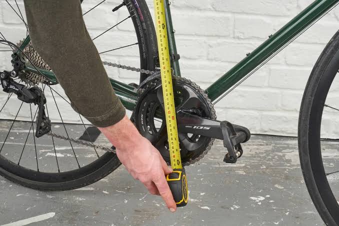 Measuring a bicycle frame with a tape measure to determine the correct bike size.