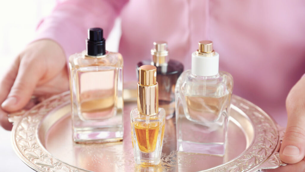 Perfume bottles displayed on a decorative tray with a pink background