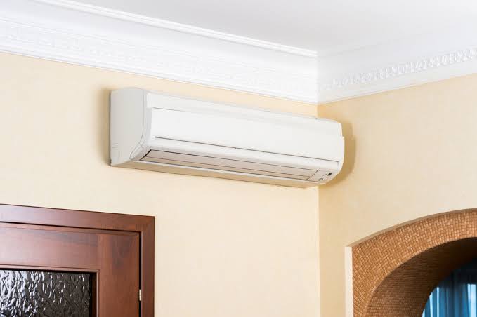 Wall-mounted split air conditioner installed above a doorway inside a room
