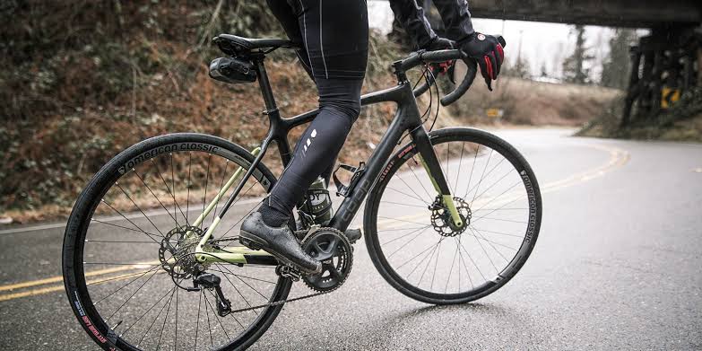 Road cyclist riding a lightweight road bike on a paved road outdoors.