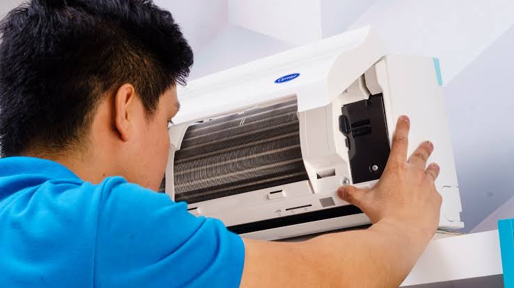 Technician inspecting and repairing a wall-mounted air conditioner indoor unit 