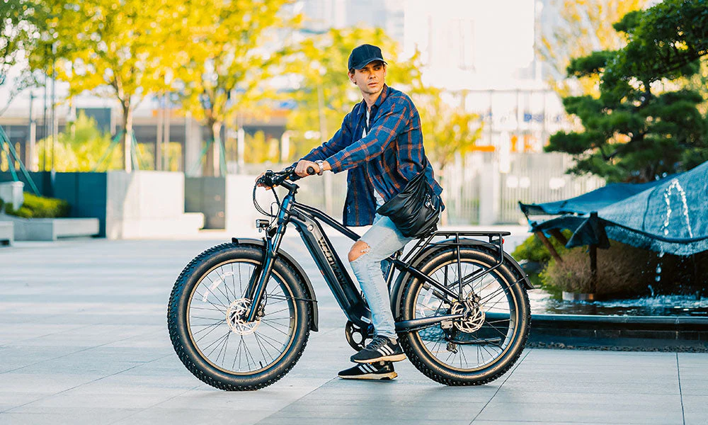 Man riding a fat-tire electric bicycle through an urban park.