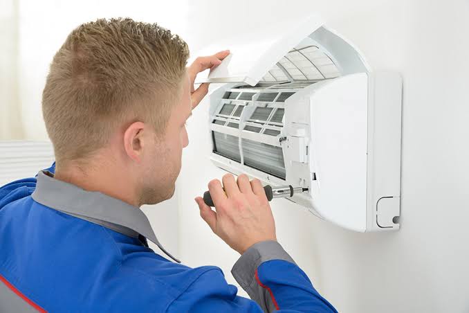 Technician inspecting and repairing the indoor unit of a split air conditioner
