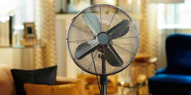 Standing fan placed in a living room with a blurred home interior background
