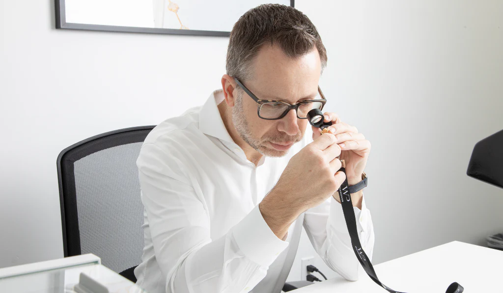 Jeweler examining a gold ring closely with a magnifying loupe.

