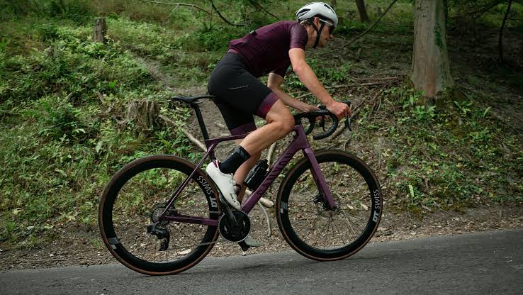 Cyclist riding a road bike in an aerodynamic position during an outdoor training session.