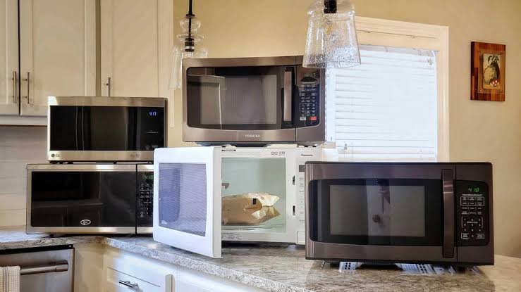 Multiple microwave ovens displayed together on a kitchen countertop.