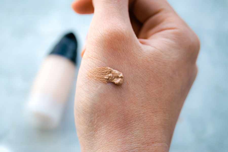 Close-up of sunscreen cream applied on hand with product bottle in background
