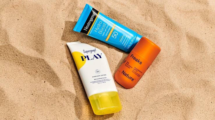 Sunscreen bottles placed on sand for summer sun protection