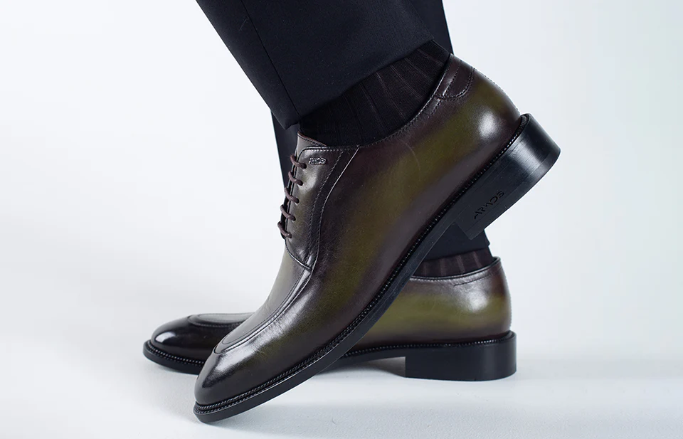 Polished black leather dress shoes worn with formal trousers.