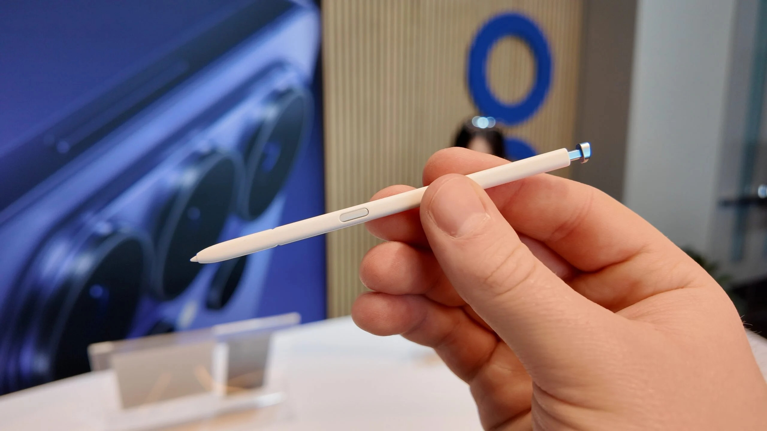Hand holding a Samsung S Pen stylus for a foldable smartphone.
