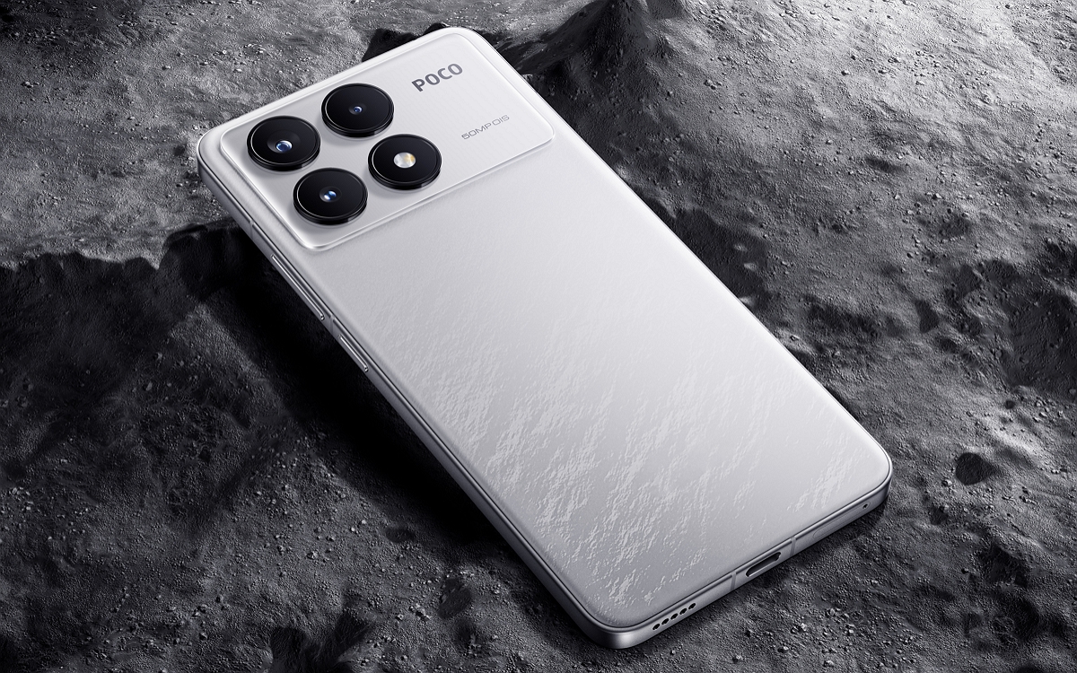 Silver Poco smartphone resting on a dark, textured lunar surface.
