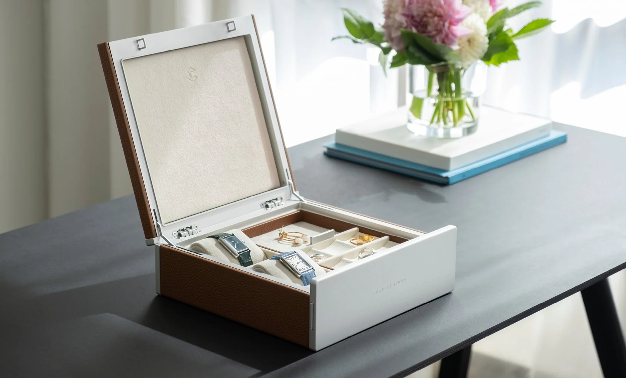 Jewelry storage box with watches, rings, and earrings organized in soft-lined compartments.