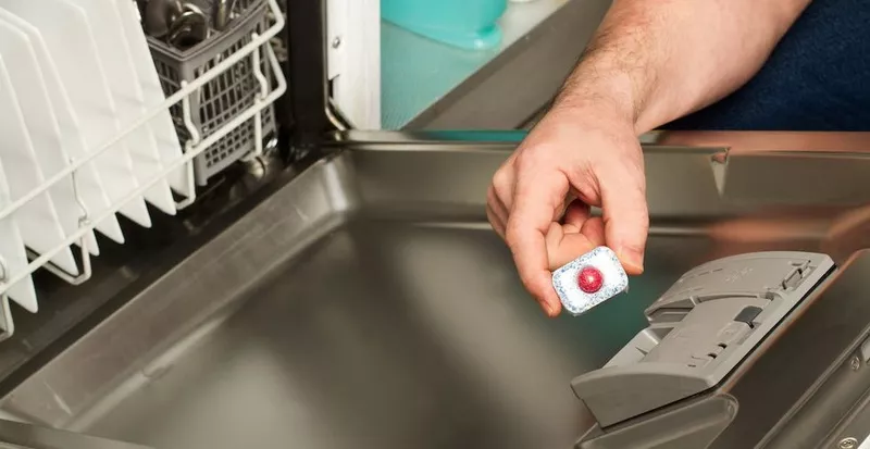Man loading dishes into a built-in dishwasher in a modern kitchen
