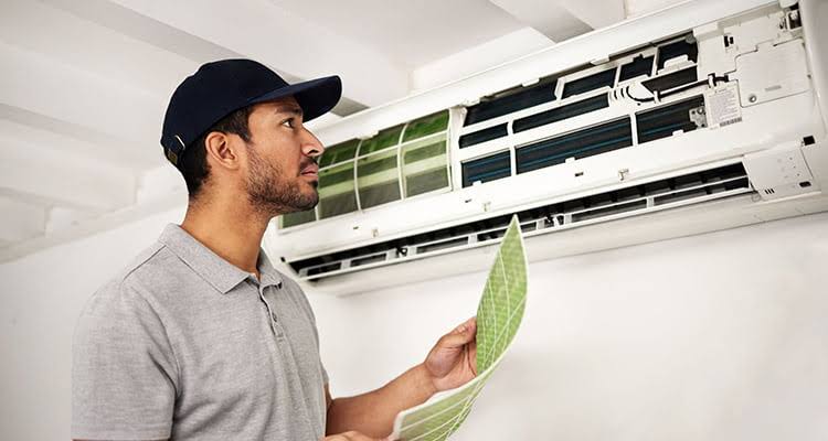 Technician inspecting and replacing the filter of a wall-mounted air conditioner