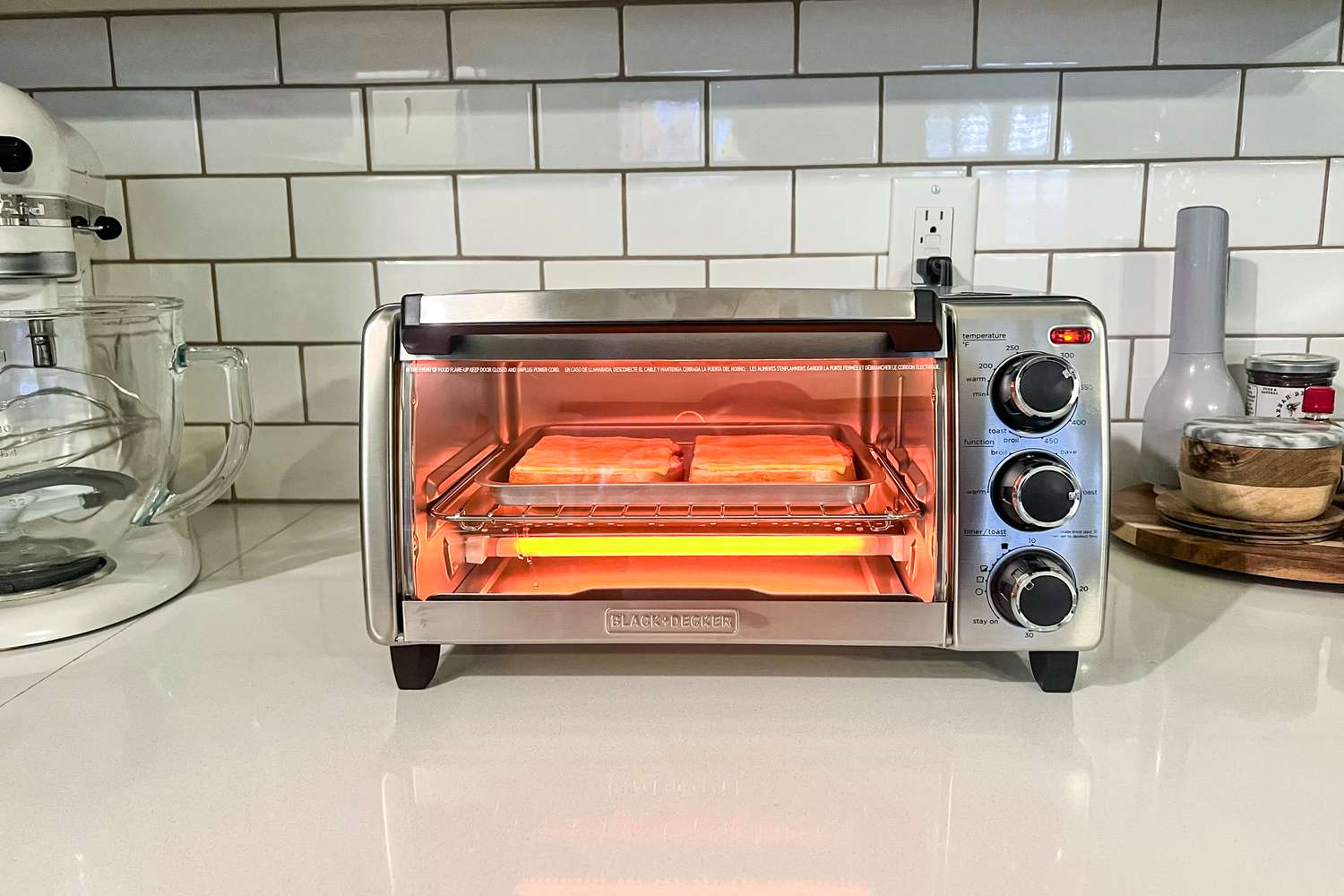 Toaster oven heating sandwiches on a kitchen countertop.