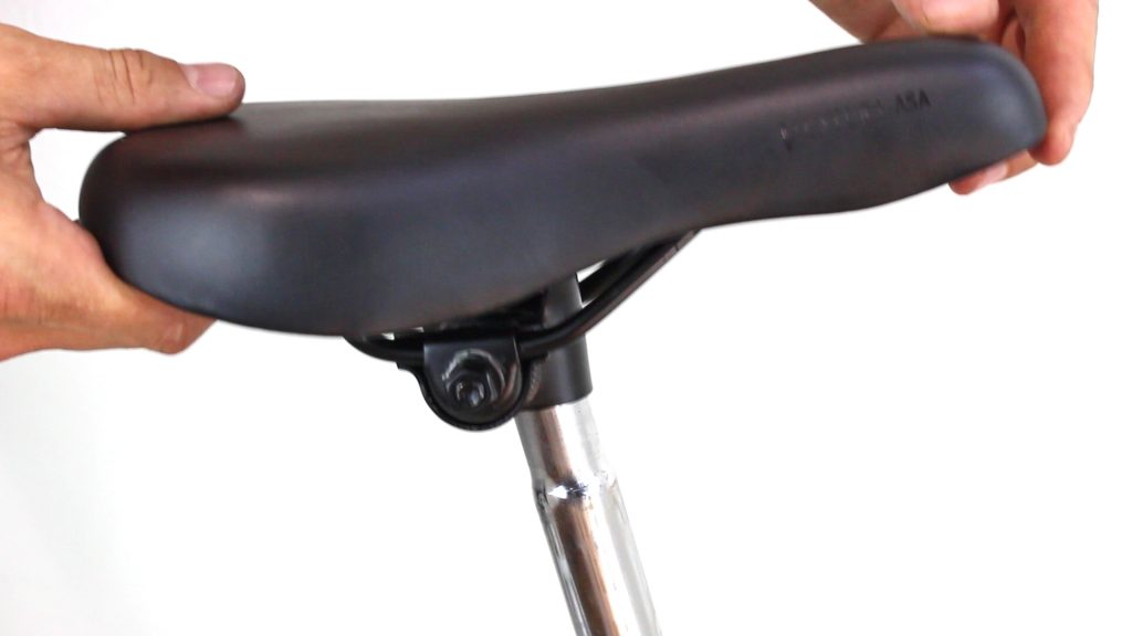 Close-up of a bicycle saddle and seatpost with hands adjusting the saddle position.