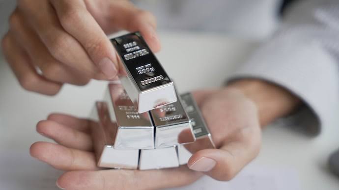 Hands holding and stacking polished silver bars of different sizes