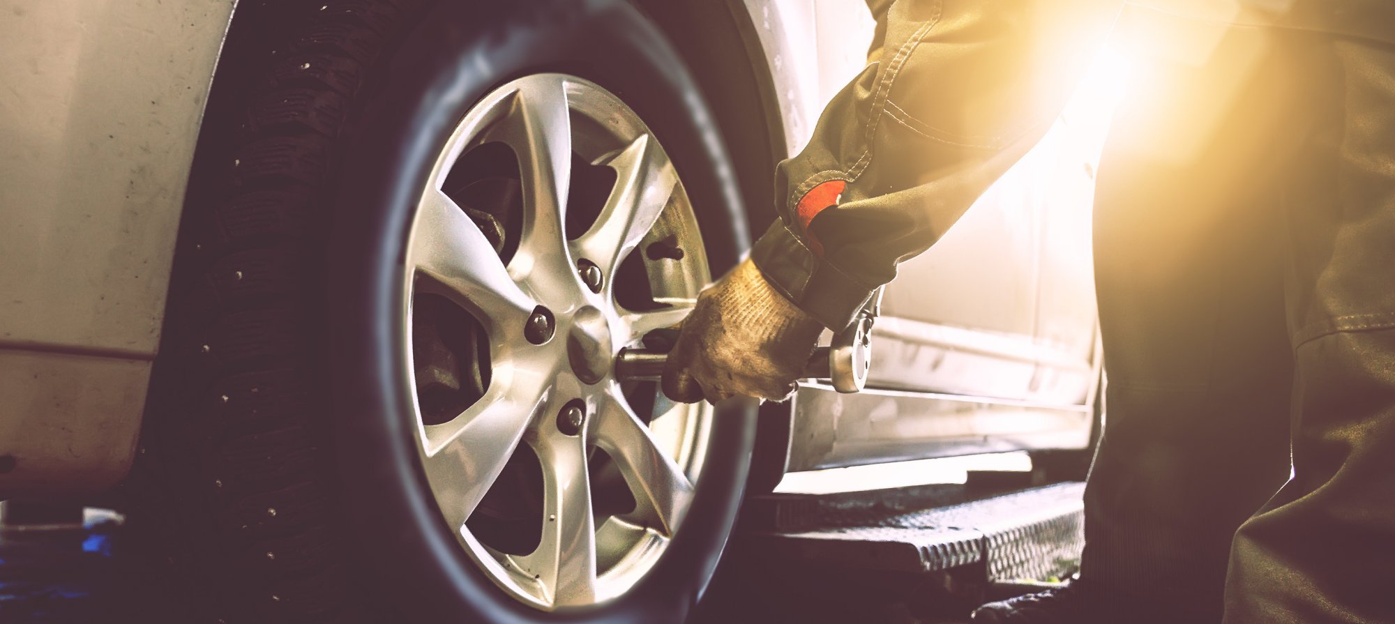 Person checking car tire pressure with a gauge near a vehicle wheel.
