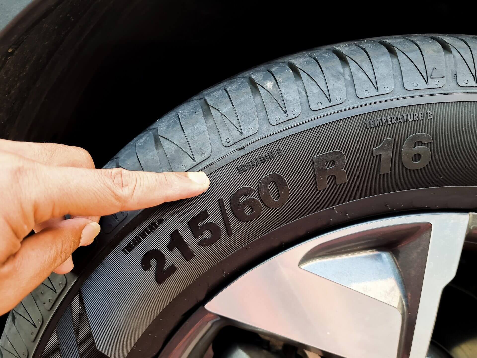 Close-up of car tire sidewall showing size marking 215/60 R16.