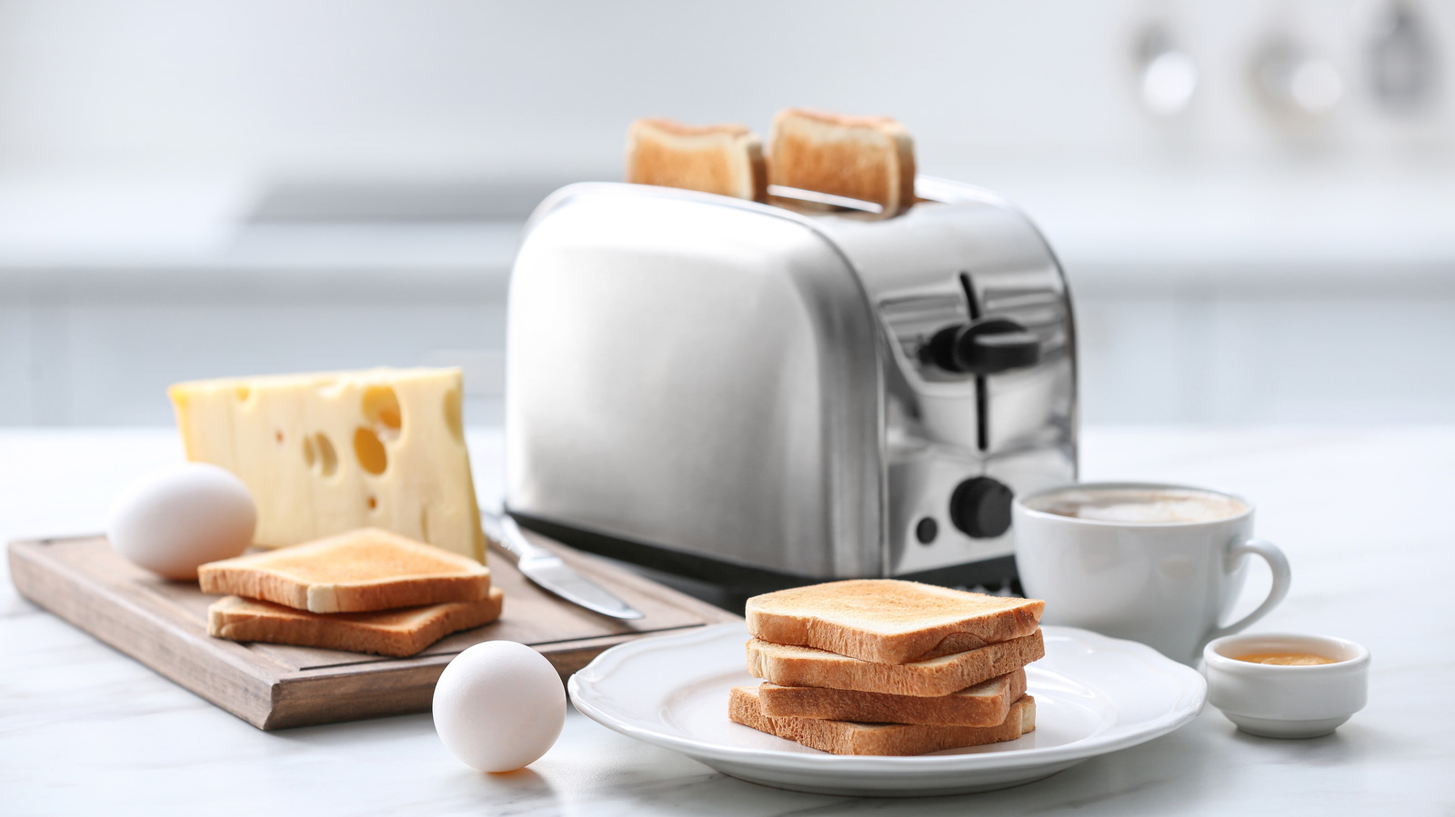 Toaster with toasted bread, eggs, cheese, and coffee arranged for breakfast.