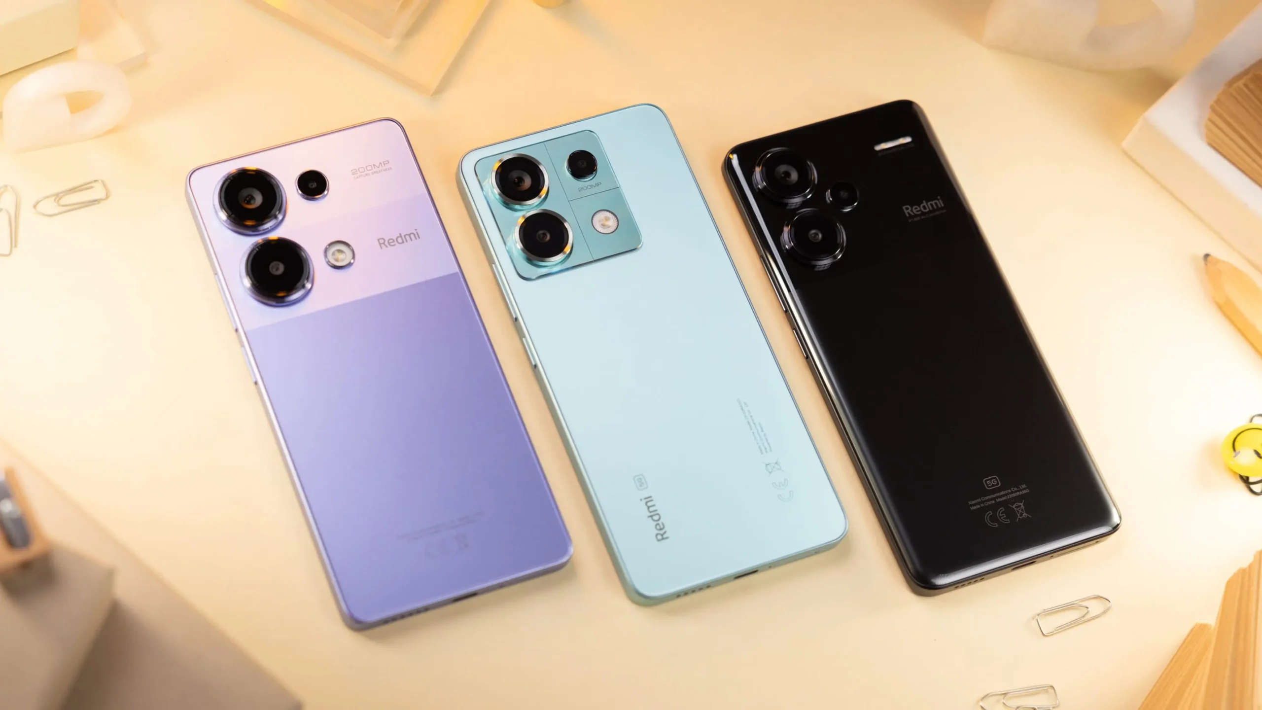 Three Redmi smartphones showcasing different colors and rear camera designs.