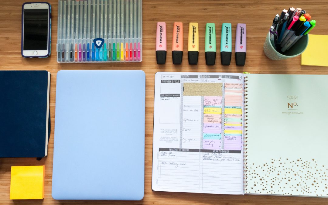Study desk with planner, notebooks, pens, highlighters, sticky notes and smartphone