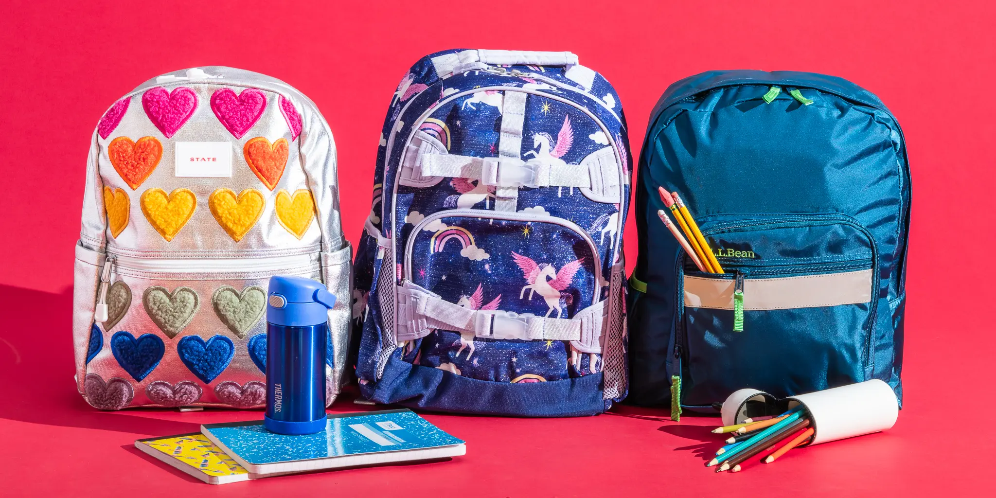 Colorful school backpacks with notebooks, pencils and water bottle