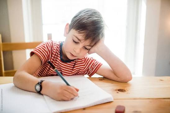 Student writing in a notebook at a desk