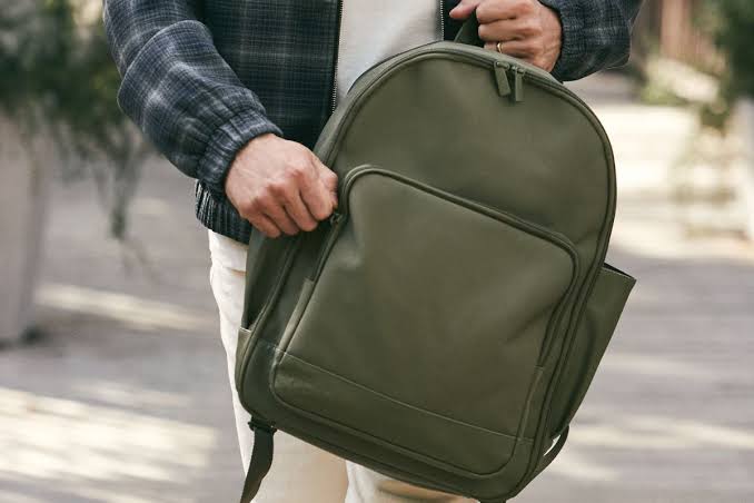 Man carrying a green laptop backpack for university or work