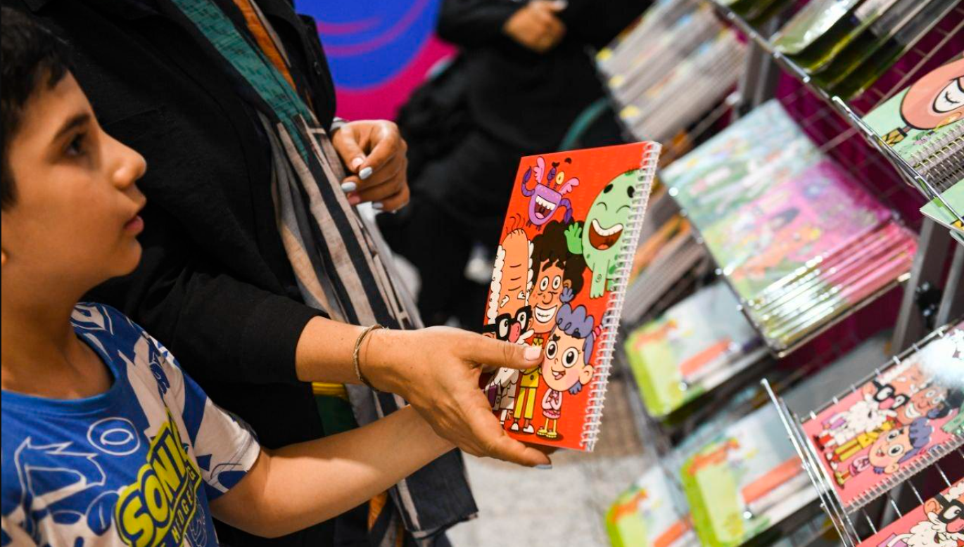 Child choosing a colorful spiral notebook in a stationery store