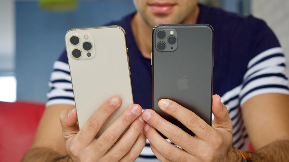 Person holding two iPhone Pro models in gold and space gray side by side
