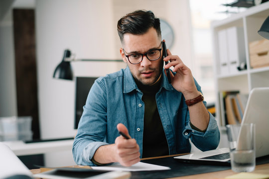 Man talking on smartphone while working at a desk in an office