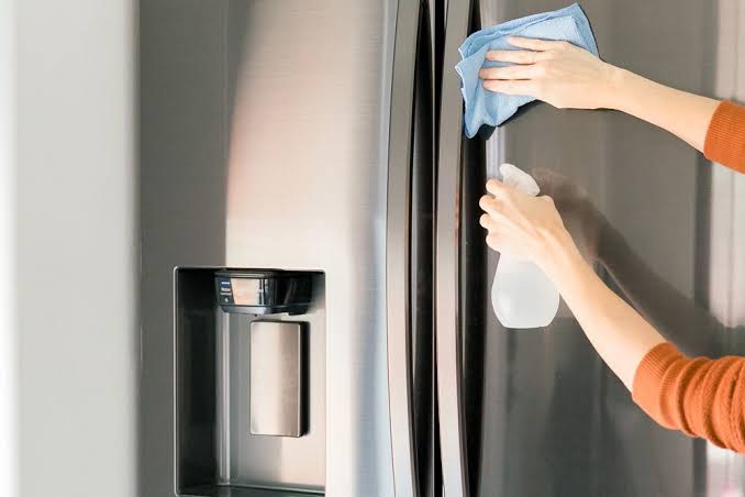 Cleaning a stainless steel refrigerator with spray and a microfiber cloth