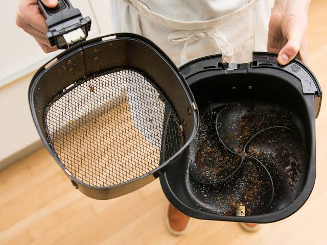 Dirty air fryer basket being removed for cleaning