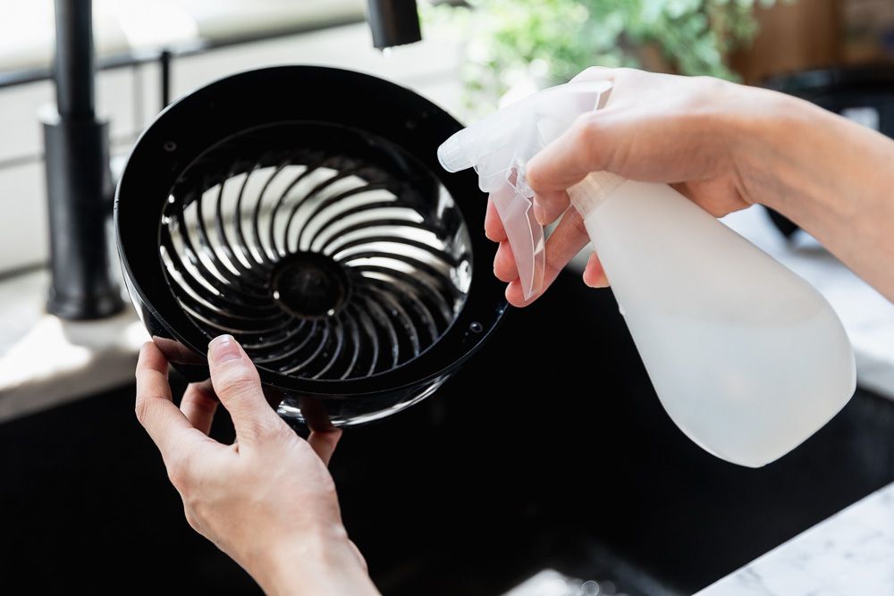 Cleaning a fan grille with a spray bottle