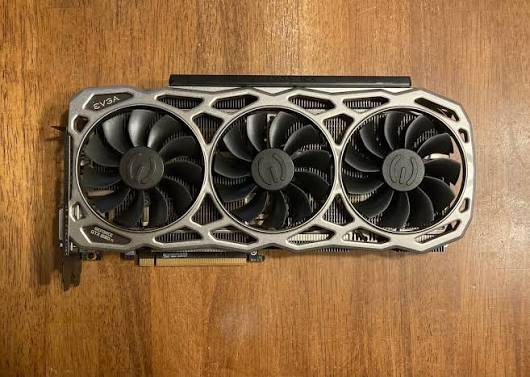 EVGA triple-fan dedicated graphics card on a wooden surface