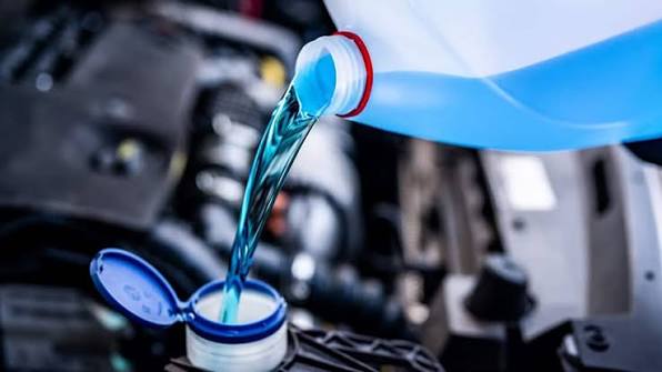 Pouring blue antifreeze coolant into a car cooling system reservoir
