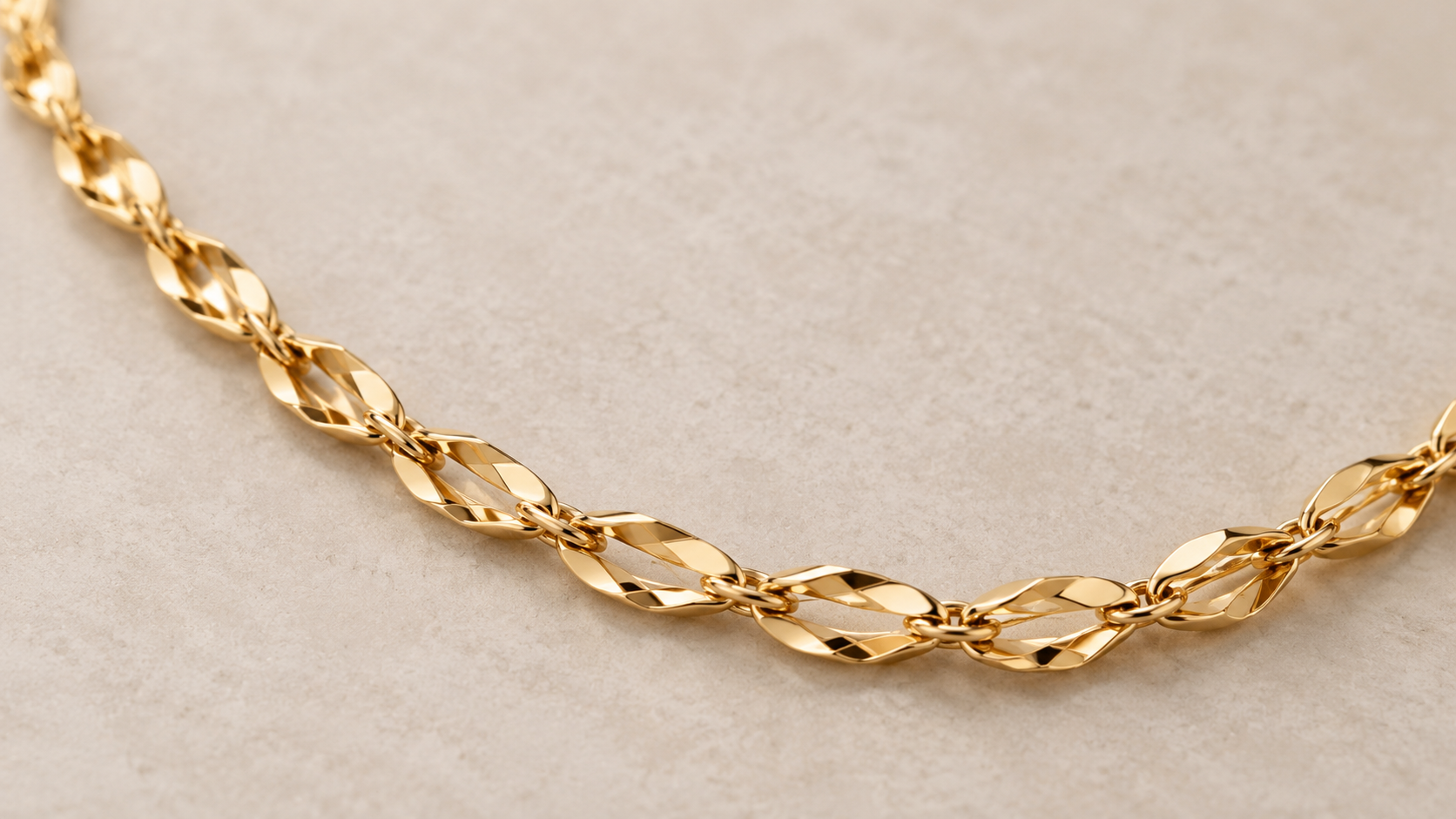 Gold flamingo chain with delicate twisted links on a neutral beige background