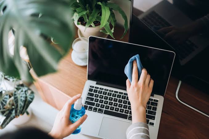 Cleaning a laptop screen with a microfiber cloth and cleaning solution