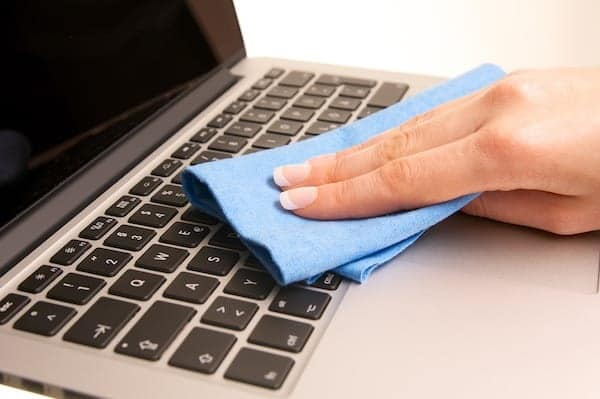 Cleaning a laptop keyboard and palm rest with a microfiber cloth