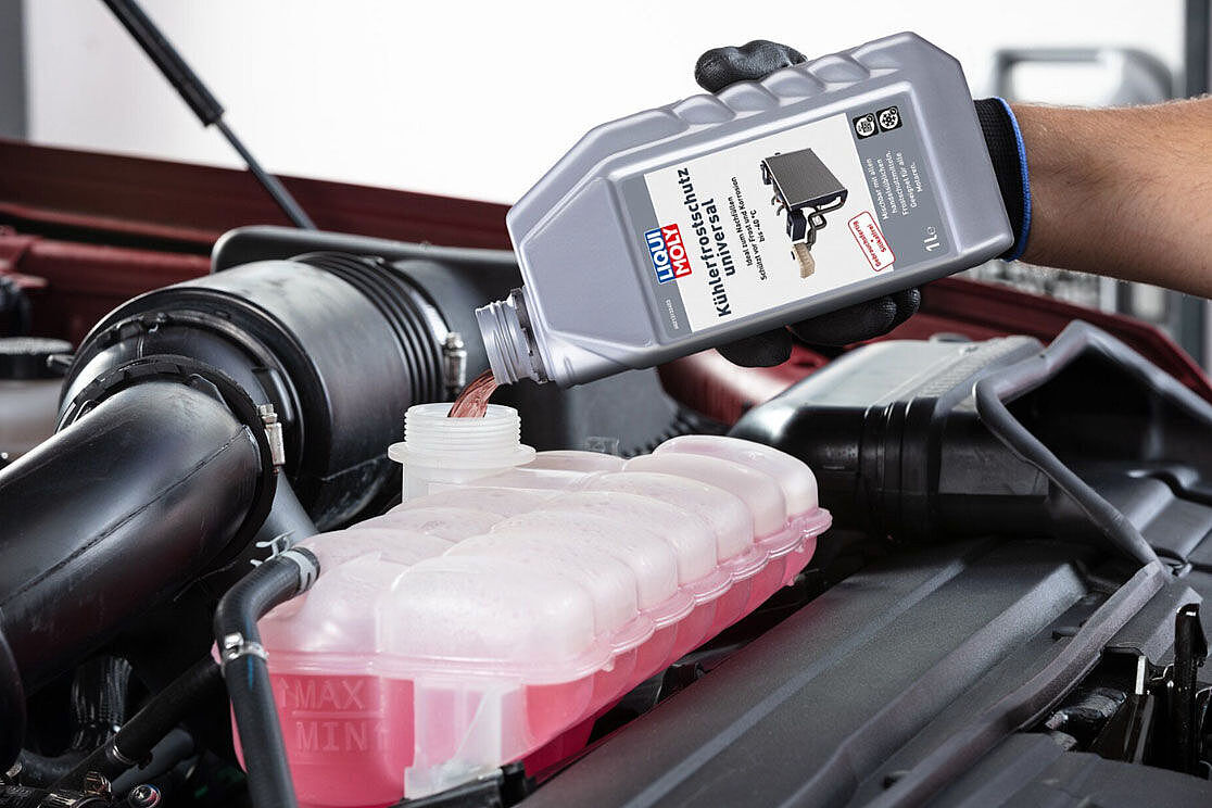 Pouring coolant into a car expansion tank during maintenance